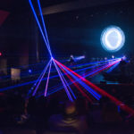 Colourful rainbow-like laser beams shooting from two spots on the stage onto the audience at Algonquin Commons Theatre