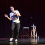 Comedian Russell Howard makes a funny waving pose one stage of the Algonquin Commons Theatre