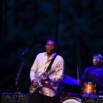 Robert Cray plays his guitar wearing a white shirt and a drummer can be seen playing the the background at the Algonquin Commons Theatre